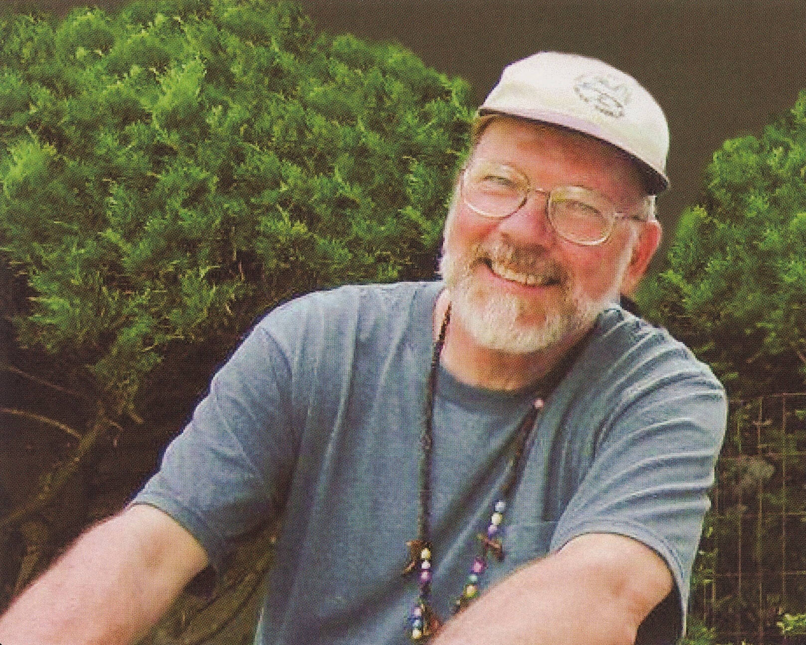 Milton E. Ford smiles, wearing a grey t-shirt and white baseball cap
